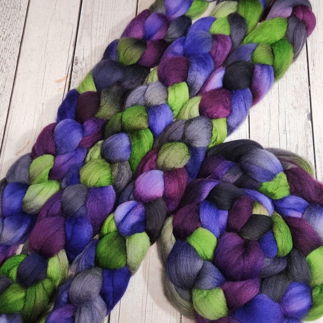 Purple and green roving on a wooden table.