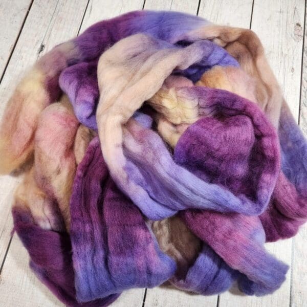 A pile of purple and pink wool on a wooden floor.