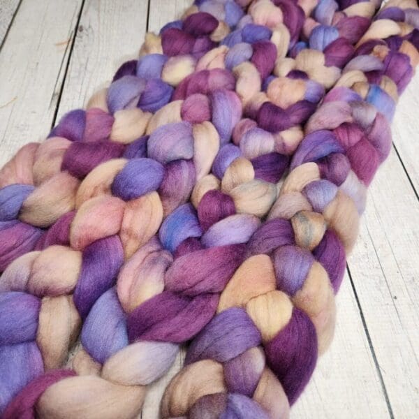 Purple and beige roving on a wooden floor.