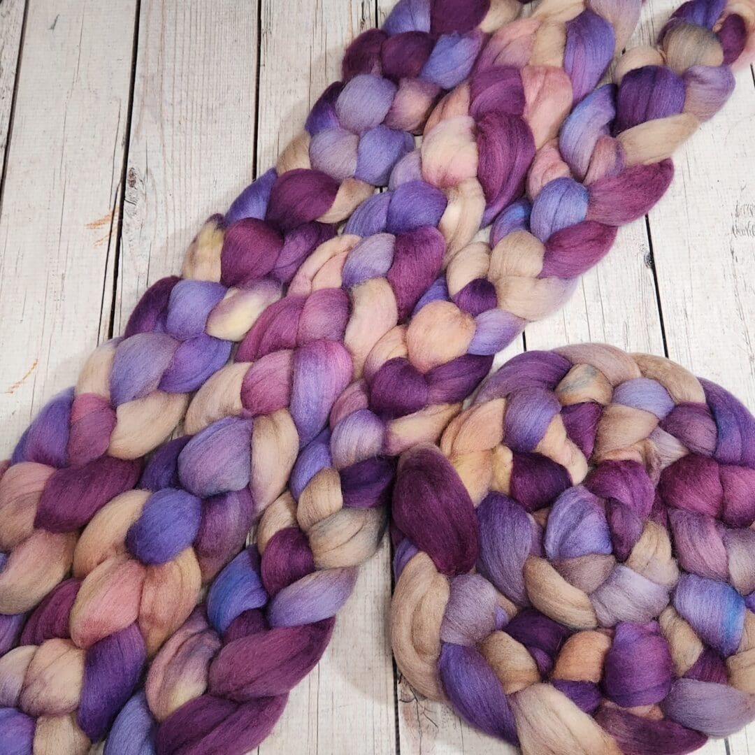 Purple and beige roving on a wooden table.