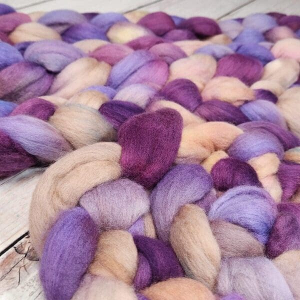 Purple and beige roving on a wooden table.