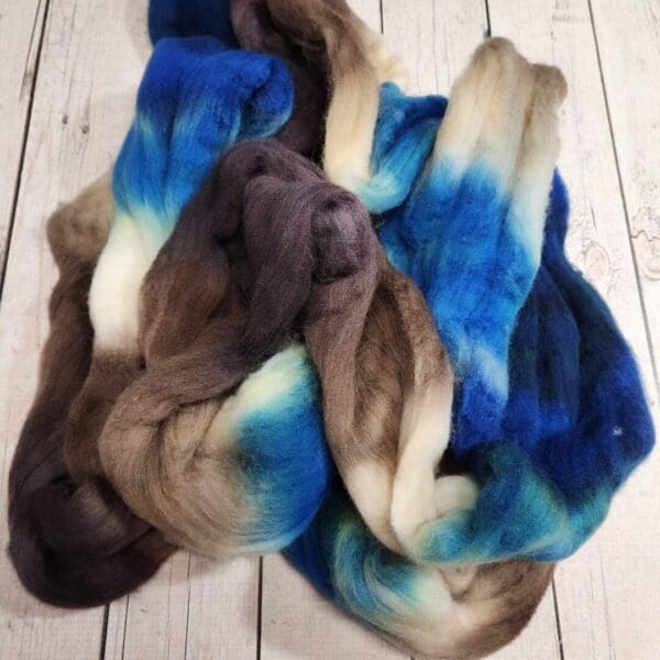 A bunch of blue and brown wool skeins on a wooden floor.