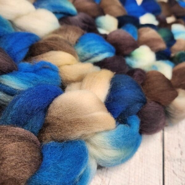 A pile of blue and brown roving on a wooden table.