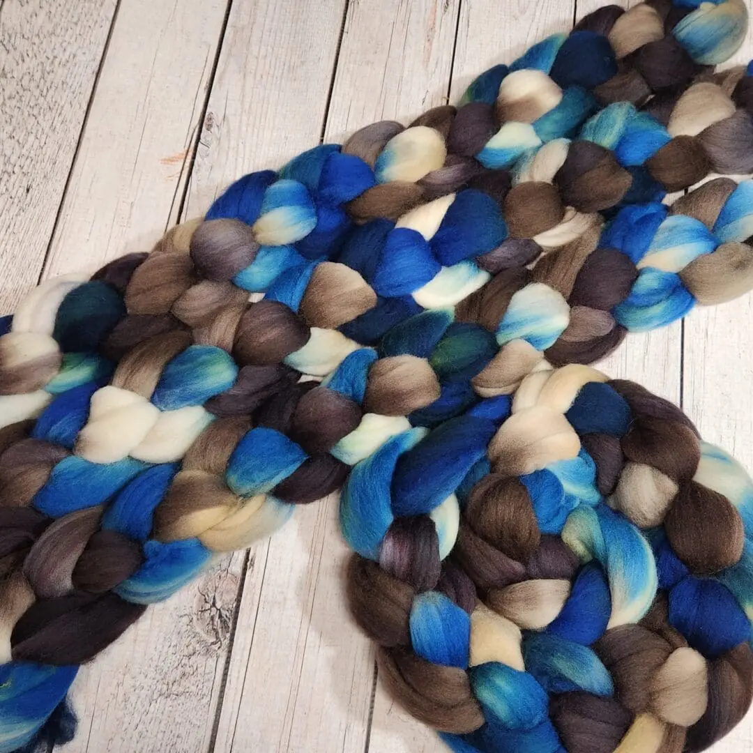 A bunch of blue and brown roving on a wooden floor.