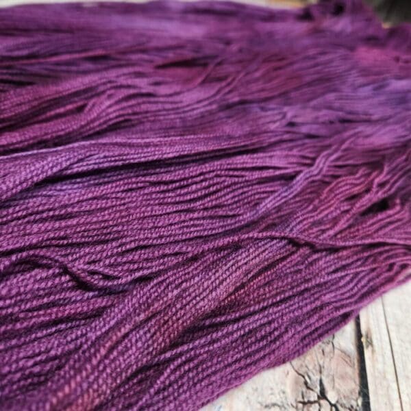 A skein of purple yarn on a wooden table.