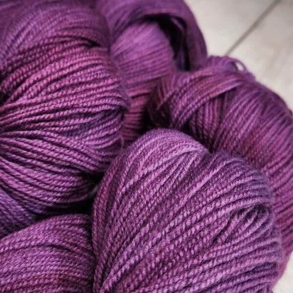 A bunch of purple skeins on a wooden table.