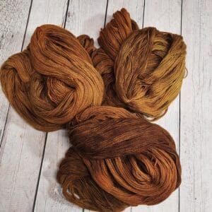 Three skeins of brown yarn on a wooden table.