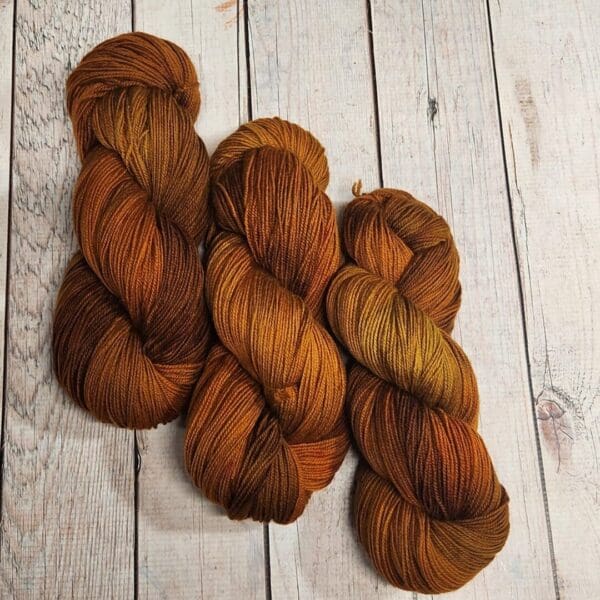 Three brown and orange skeins on a wooden table.