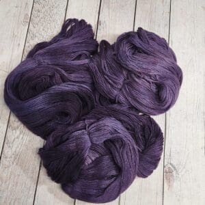 A bunch of purple yarn on a wooden floor.