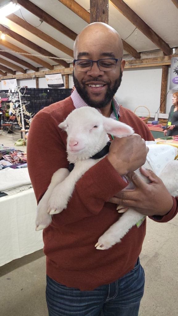 A man holding a baby lamb.