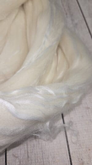 Soft natural wool roving on rustic wood