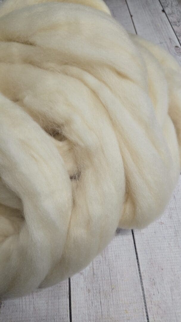 Loose cream roving fibers on wooden floor