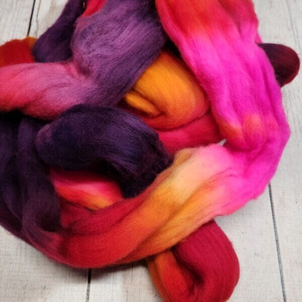 A bunch of colorful roving on a wooden table.
